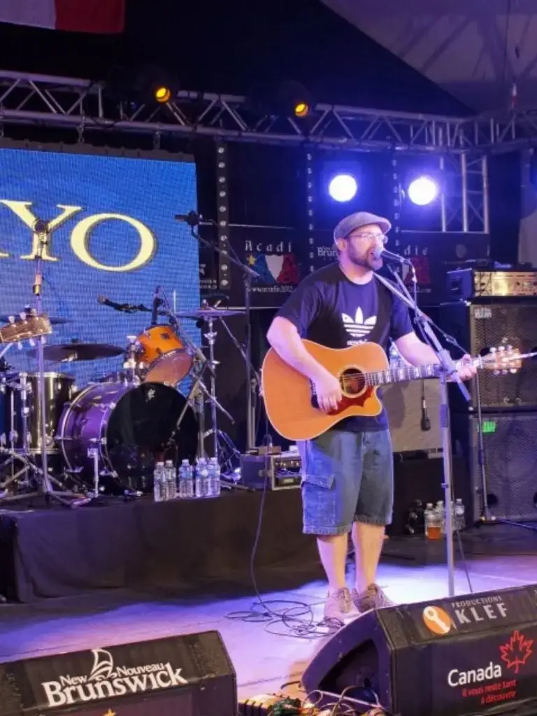 Musician performing with guitar on stage at a concert.